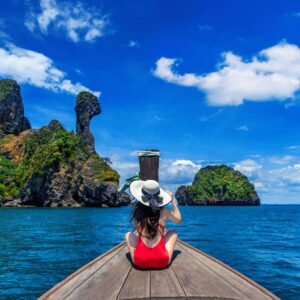 Woman traveler sitting on boat enjoying views of limestone mount