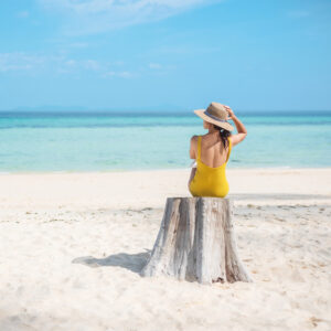Woman tourist in yellow swimsuit and hat, solo traveller looking